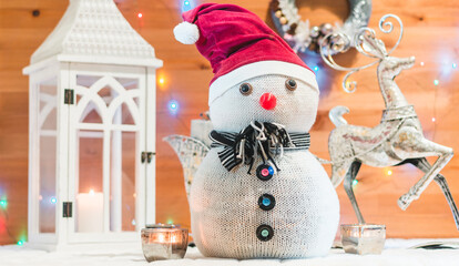 Snowman in a red cap and lights with wooden background. Christmas decoration
