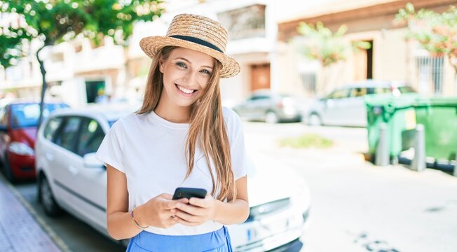 Young blonde woman on vacation smiling happy using smartphone at street of city