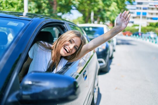 Young beautiful blonde woman smiling happy sitting at the car with hand out and cheerful expression