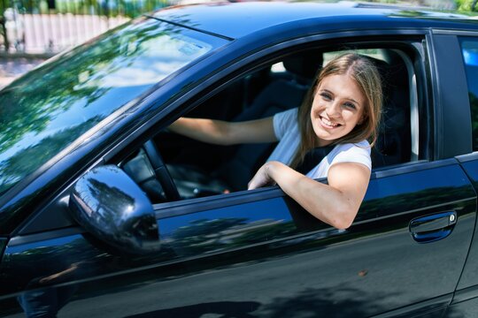 Young beautiful blonde woman smiling happy driving car