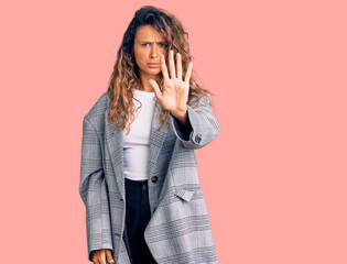 Young hispanic woman with tattoo wearing business oversize jacket doing stop sing with palm of the hand. warning expression with negative and serious gesture on the face.