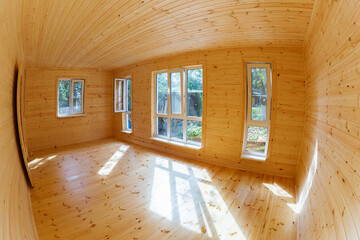 A room in a new wooden house, outside the city, with a larch floor, pine walls and large modern windows, the ceiling is also wooden.