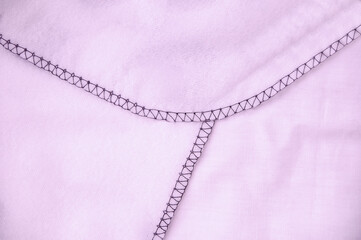 Close-up of an overlock seam on pink plaid. Home textiles.