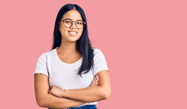 Young beautiful asian girl wearing casual clothes and glasses happy face smiling with crossed arms looking at the camera. positive person.