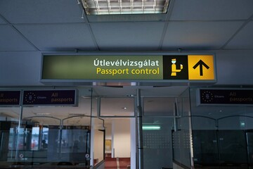 Signs for the border passport control at an international airport terminal, also written in...