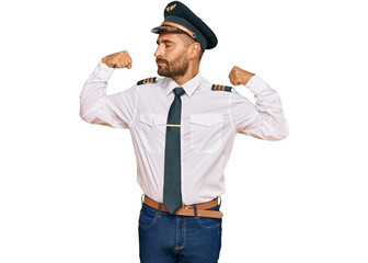 Handsome man with beard wearing airplane pilot uniform showing arms muscles smiling proud. fitness concept.
