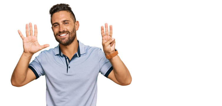 Handsome man with beard wearing casual clothes showing and pointing up with fingers number eight while smiling confident and happy.