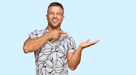 Handsome muscle man wearing casual clothes amazed and smiling to the camera while presenting with hand and pointing with finger.