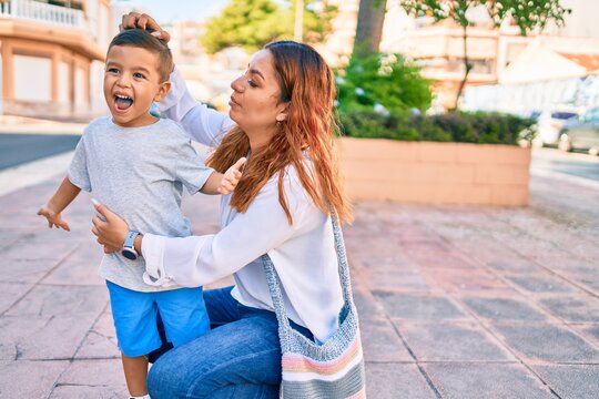 Adorable latin mother and son smiling happy hugging at the city.