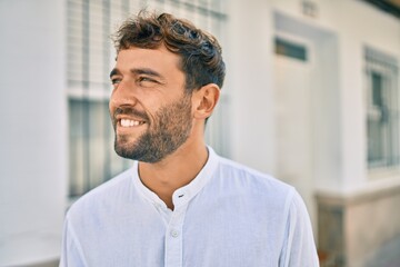 Handsome man with beard wearing casual white shirt on a sunny day smiling happy outdoors - Powered by Adobe