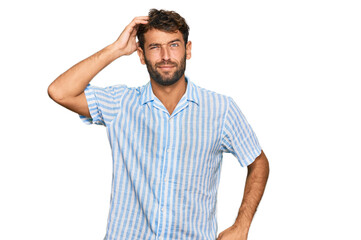 Handsome young man with beard wearing casual fresh shirt confuse and wonder about question. uncertain with doubt, thinking with hand on head. pensive concept.