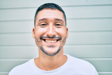 Young hispanic man smiling happy walking at street of city.