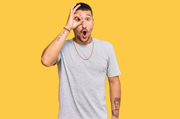 Handsome man with tattoos wearing 90s style doing ok gesture shocked with surprised face, eye...