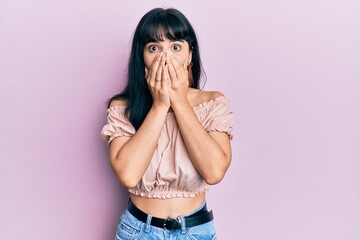 Young hispanic girl wearing casual clothes shocked covering mouth with hands for mistake. secret concept.