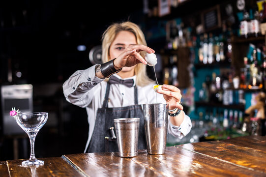 Girl barman formulates a cocktail in the taproom