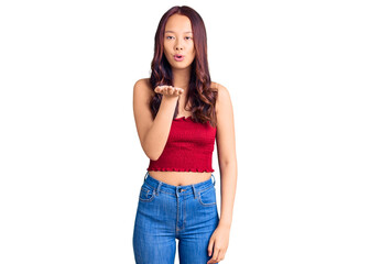 Young beautiful chinese girl wearing casual clothes looking at the camera blowing a kiss with hand on air being lovely and sexy. love expression.