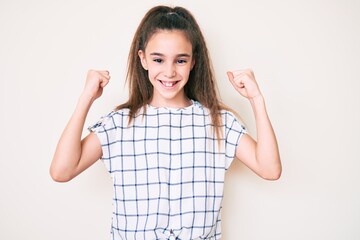 Cute hispanic child girl wearing casual clothes screaming proud, celebrating victory and success very excited with raised arms