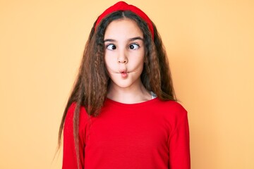 Cute hispanic child girl wearing casual clothes and diadem making fish face with lips, crazy and comical gesture. funny expression.