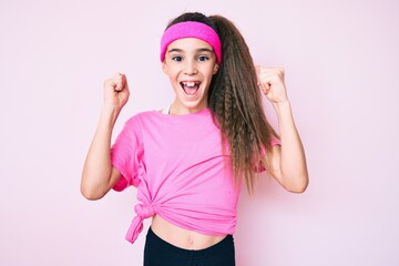 Obraz na płótnie Canvas Cute hispanic child girl wearing sportswear screaming proud, celebrating victory and success very excited with raised arms