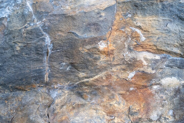 Multicolored rock wall. Stone textured surface close-up. Copy space. Abstract natural background.
