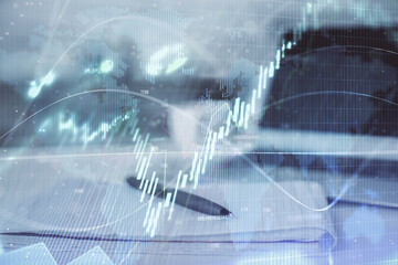 Double exposure of financial graph drawings and desk with open notebook background. Concept of...