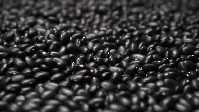 Black beans close up. Abstract pattern. Rotation. Selective focus. Slow motion