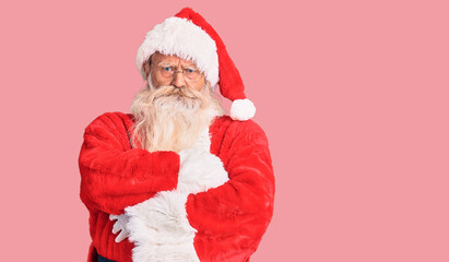 Old senior man with grey hair and long beard wearing traditional santa claus costume skeptic and...