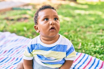 Adorable african american toddler sitting on the grass at the park.
