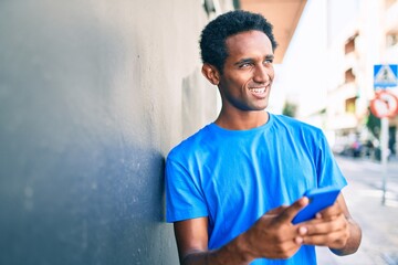 Handsome black african man smiling happy outdoors using smartphone