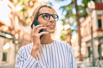 Young blonde businesswoman smiling happy talking on the smartphone at the city.