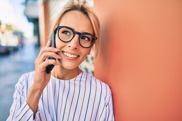 Young blonde businesswoman smiling happy using smartphone at the city.
