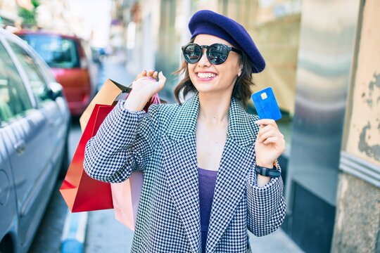 Young beautiful girl smiling happy with french style holding shopping bags and credit card at street of city