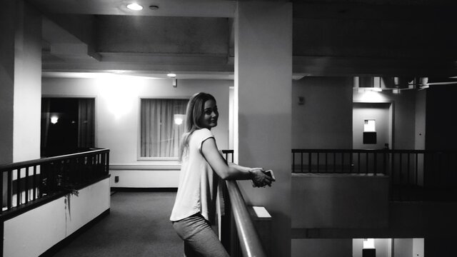 Side View Portrait Of Young Woman Standing By Railing In Building At Night