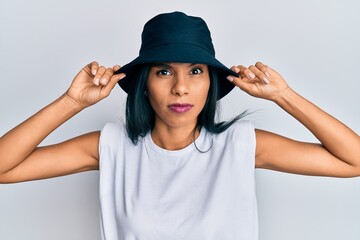 Young african american woman wearing fashion hat skeptic and nervous, frowning upset because of...