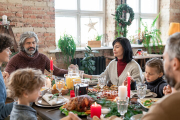 Three generations of large family holding by hands while praying before dinner