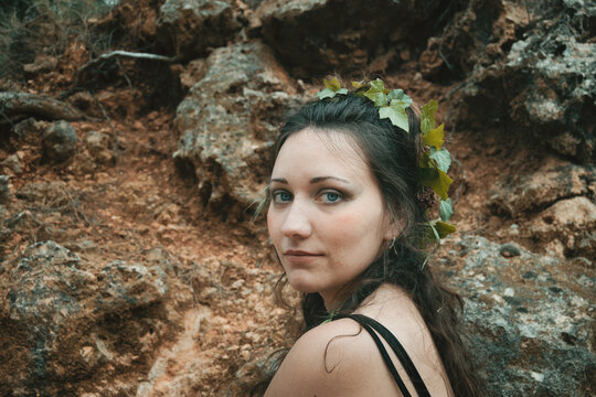 Portrait Of Young Woman Wearing Leaf Against Rocks In Forest