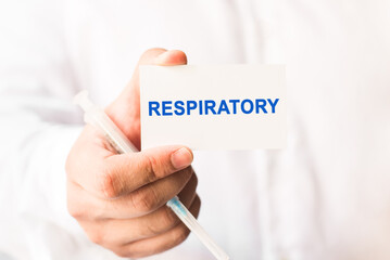 Word respiratory on a white background with a syringe in hand. Medicine concept