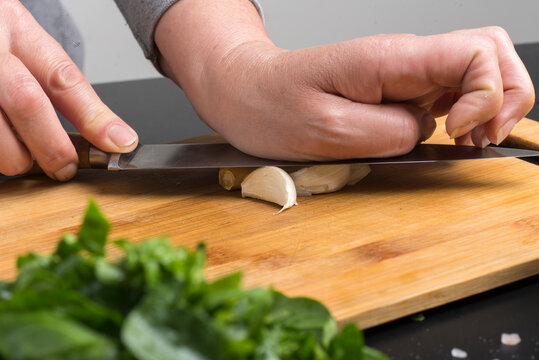 cook crushes the garlic with a knife