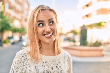 Young blonde girl smiling happy standing at the city.