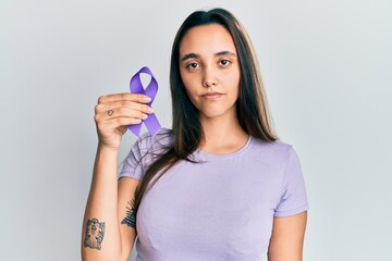 Young hispanic woman holding purple ribbon awareness smiling happy pointing with hand and finger