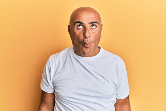 Mature middle east man wearing casual white tshirt making fish face with lips, crazy and comical gesture. funny expression.