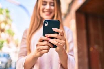 Young caucasian girl smiling happy using smartphone at the city.