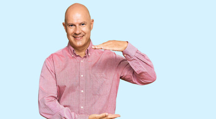 Middle age bald man wearing casual clothes gesturing with hands showing big and large size sign, measure symbol. smiling looking at the camera. measuring concept.