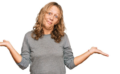 Middle age blonde woman wearing casual clothes clueless and confused expression with arms and hands...