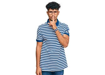 Fototapeta na wymiar Young arab man wearing casual clothes and glasses asking to be quiet with finger on lips. silence and secret concept.