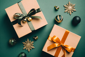 Christmas flat lay composition. Carton gift boxes with ribbon bows, balls and golden snowflakes on dark green background. Vintage, retro style.