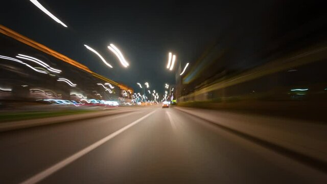 Amazing motion timelapse of the night rush drive in a big city. Speedy car driving the highway with a lot of lights and traffic, overtaking other vehicles and passing by skyscrapers along the road.