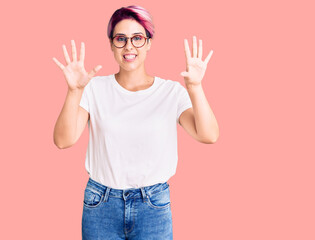 Obraz premium Young beautiful woman with pink hair wearing casual clothes and glasses showing and pointing up with fingers number ten while smiling confident and happy.
