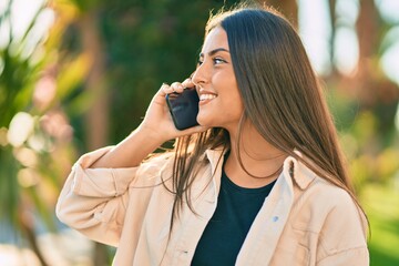 Young hispanic girl smiling happy talking on the smartphone at the park.