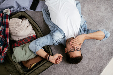 Young smiling man packing clothes into travel bag. Man preparing for the trip..